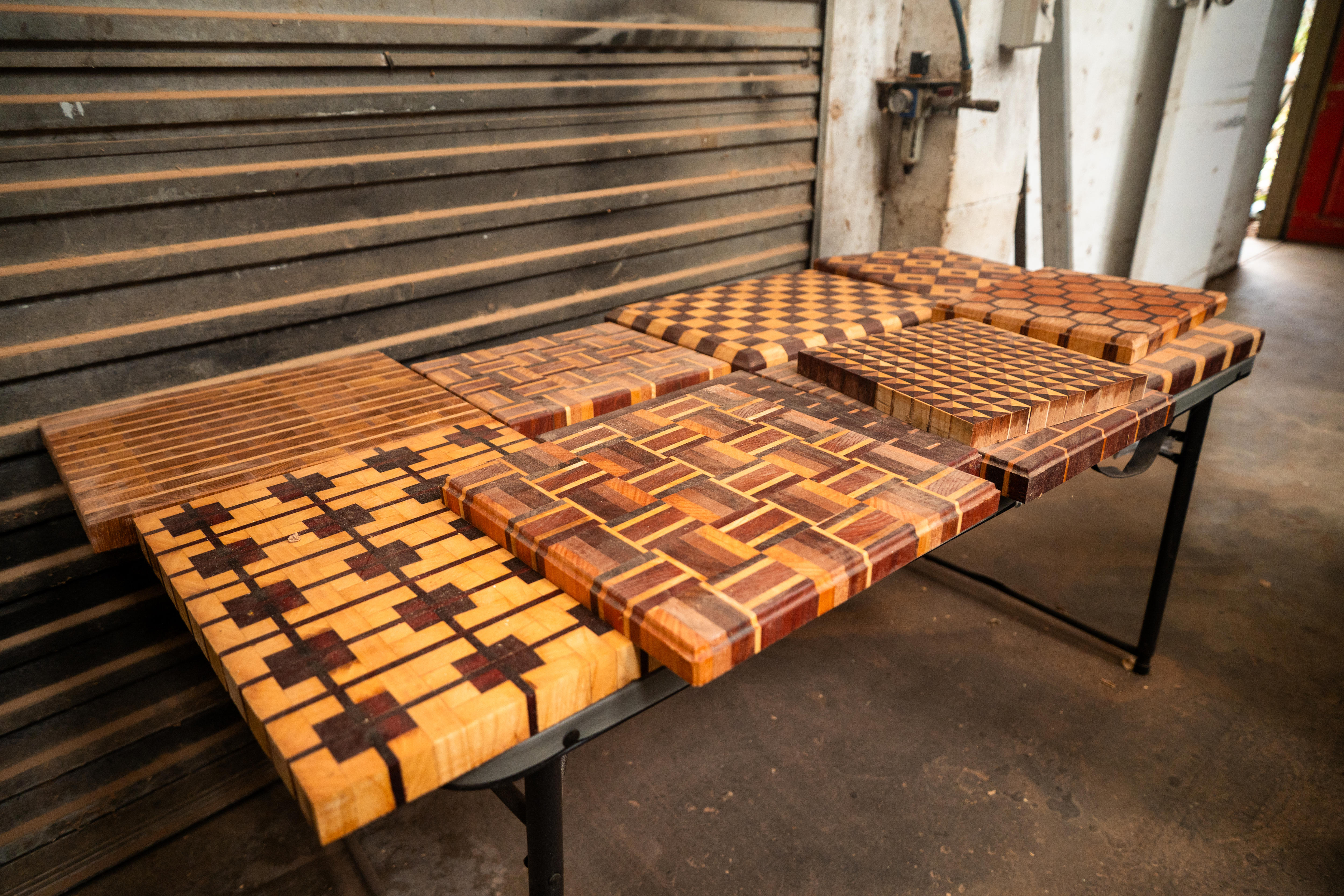 wooden cutting boards, with geometric patterns, sitting on a bench in a shed