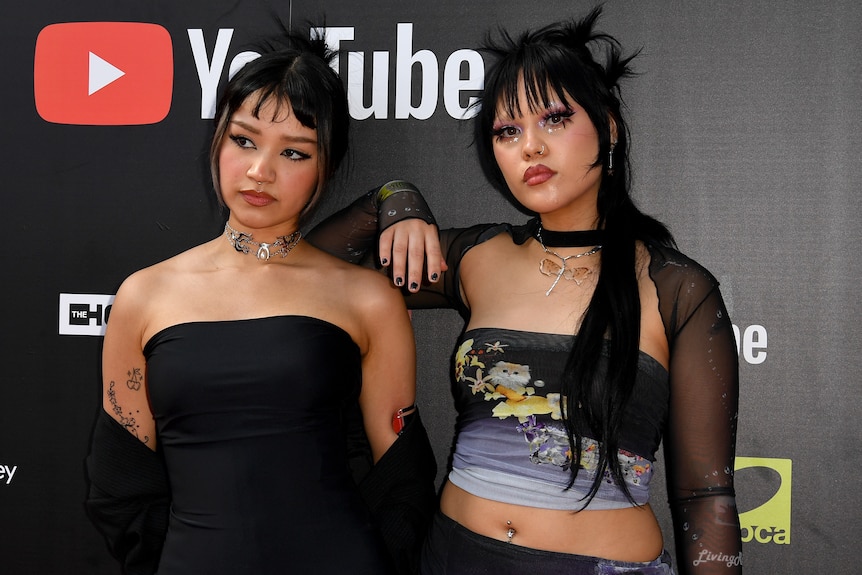 Cat and Calmell, both with choker-style chains.  Cat wears a black strapless top, Camell wears a black and purple top