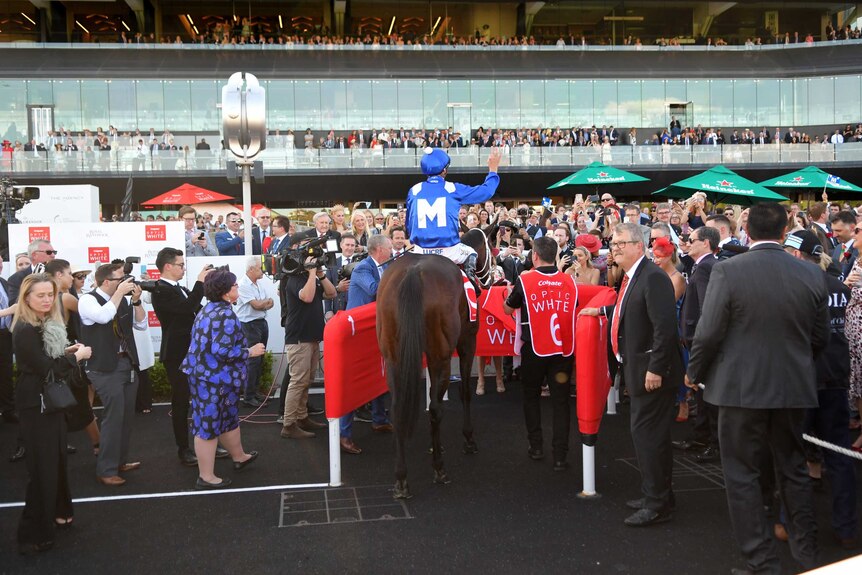 Hug Bowman waves to the crowd on top of Winx after returning to scale at Randwick.