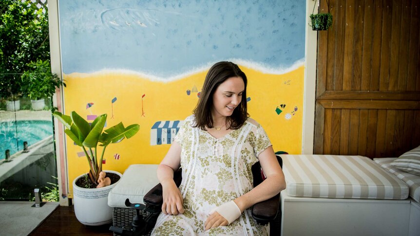 Jess Collins sits in her home in front of a mural she and her siblings painted as children of the beach.