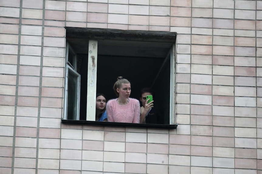 A girl looks out of a quarantined building.