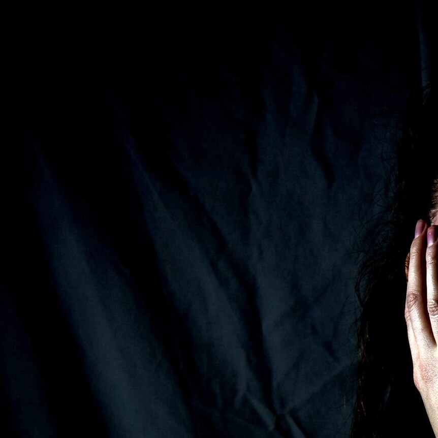 Half a scared woman's face in frame with a dark background