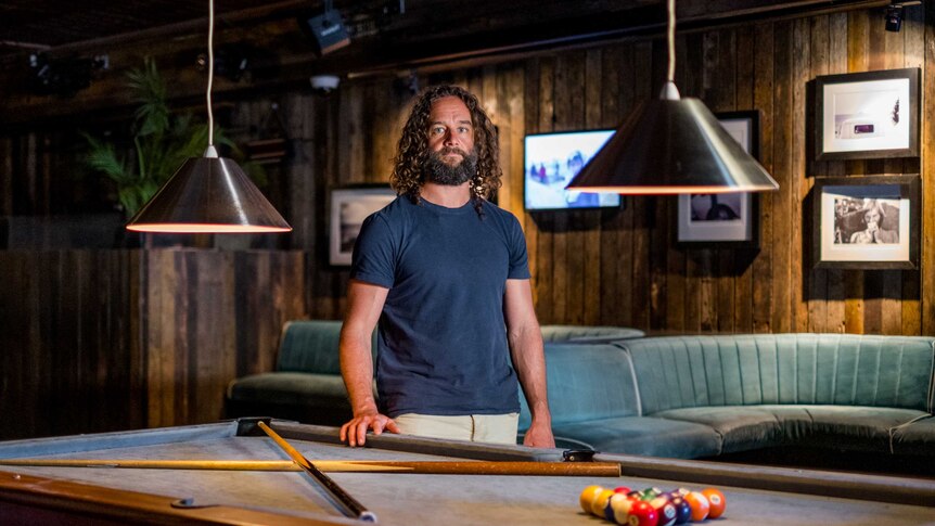 Loren Nowland stands at a pool table in his empty nightclub.