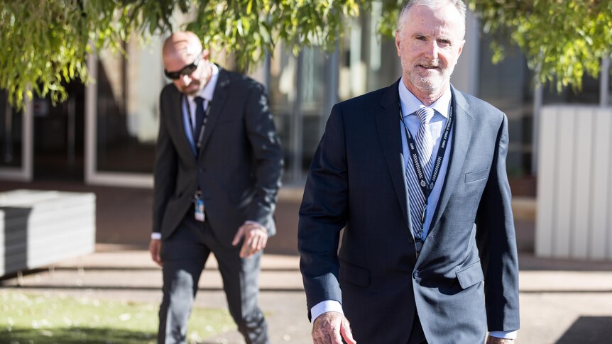 Two male detectives in suits and ties walking out of court.  