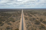 A road stretches off into the horizon, not a vehicle in sight