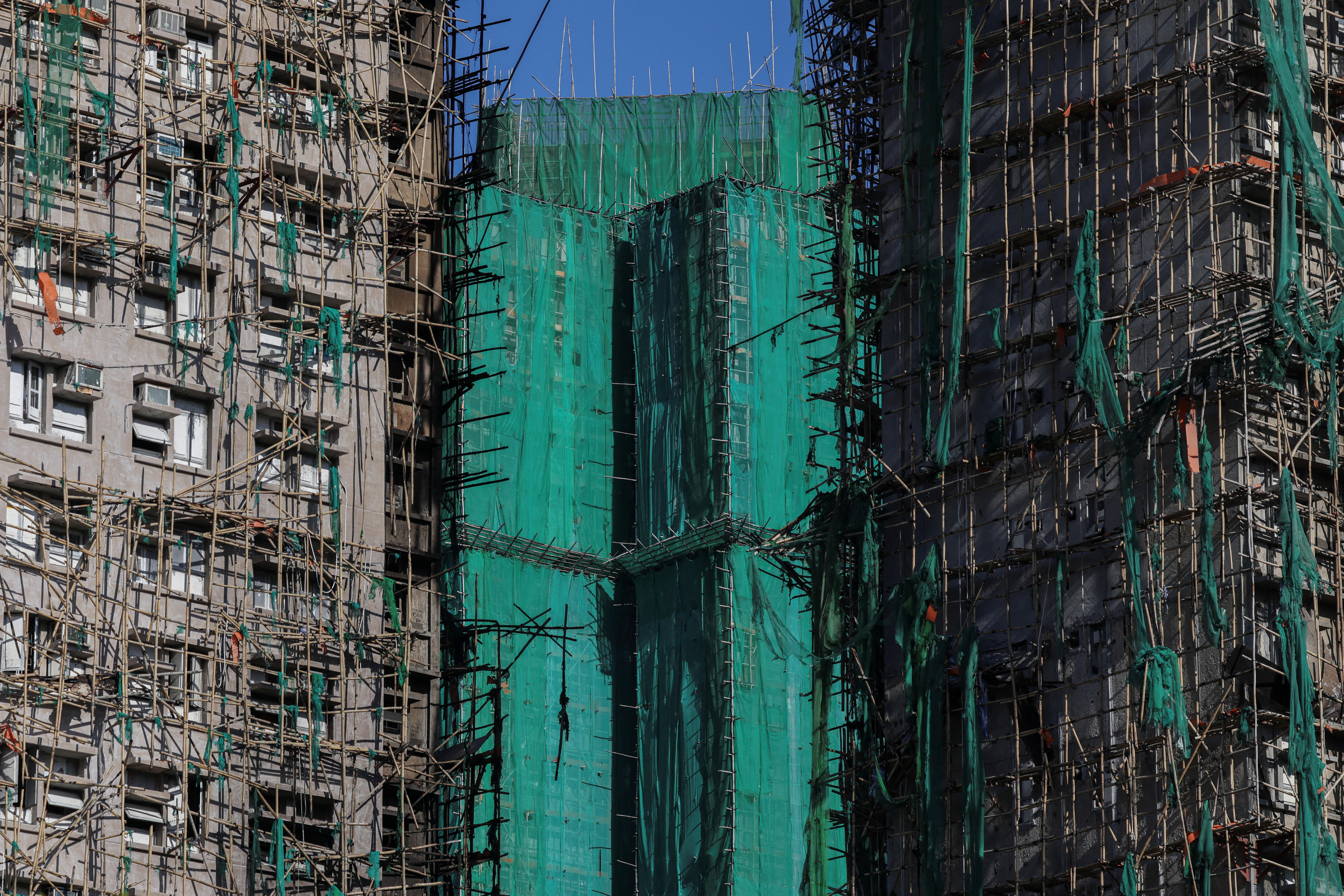 Primer plano de dos torres quemadas con andamios de bambú y un edificio sin quemar entre ellas