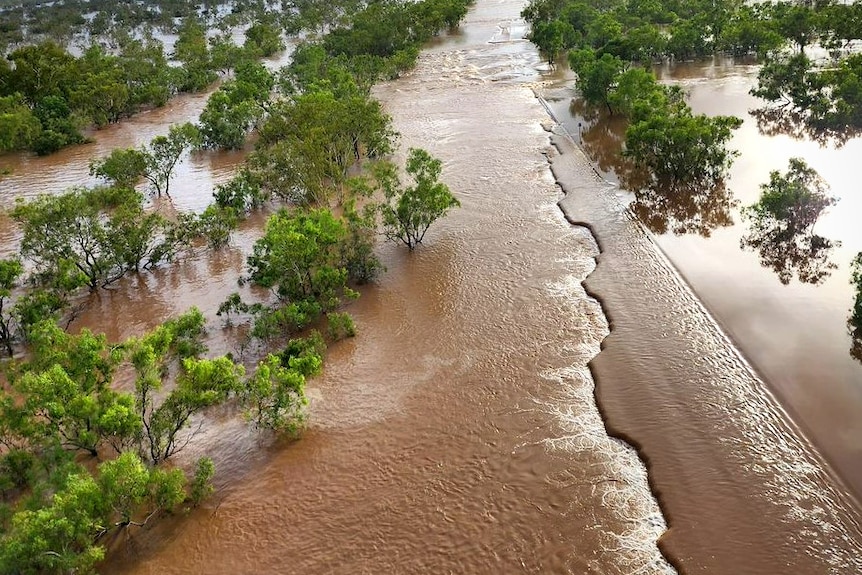 A badly damaged Great Northern Highway partially submerged under flood waters.