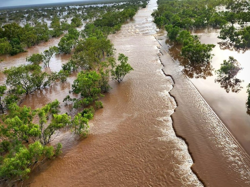 A badly damaged Great Northern Highway partially submerged under flood waters.