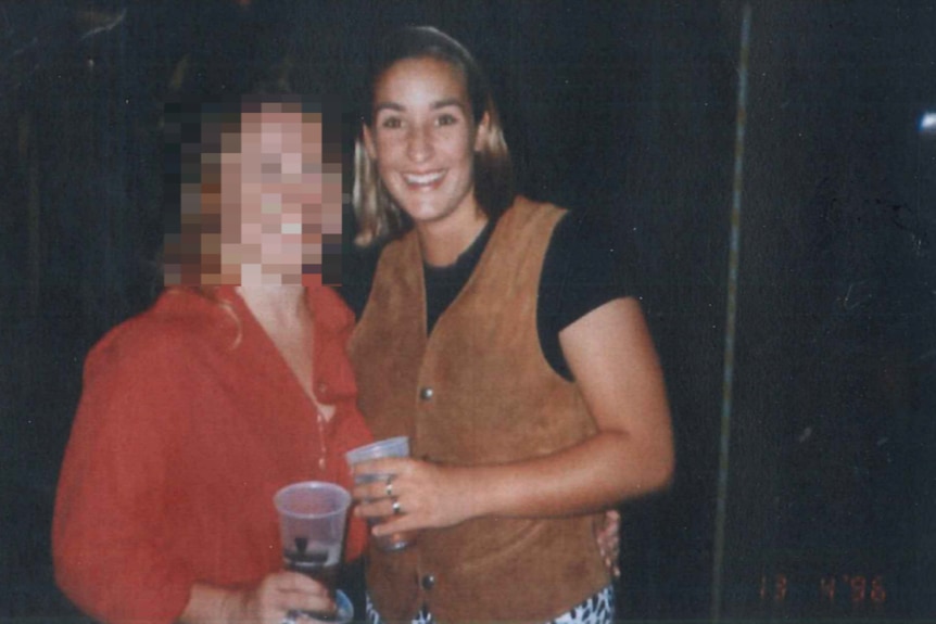 An old looking colour photo of two young woman, the lady on the left blurred, the lady on the right smiling.