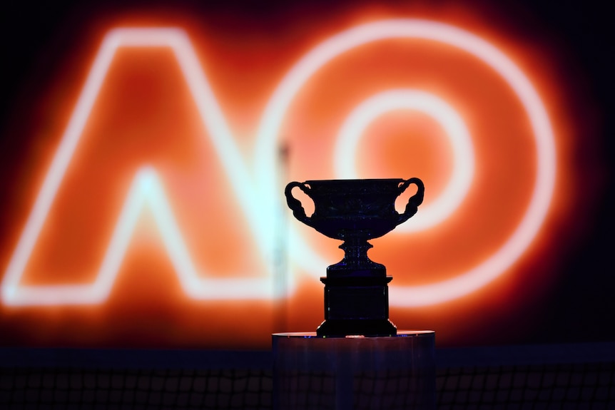 The Australian Open mens final trophy on display ahead in front of an illuminated AO.