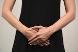 A woman with her hands clasped in front of her stomach