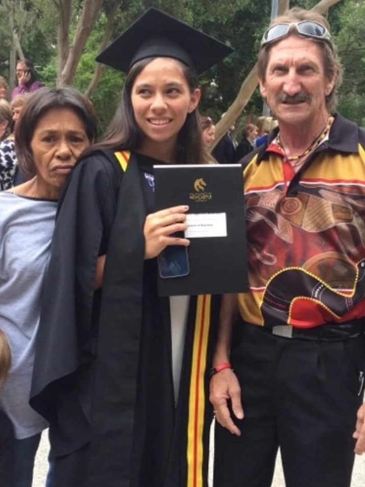 A woman posing for a graduation photo with her parents.