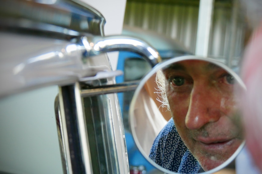 Close up of man's face in round mirror of vintage Holden car