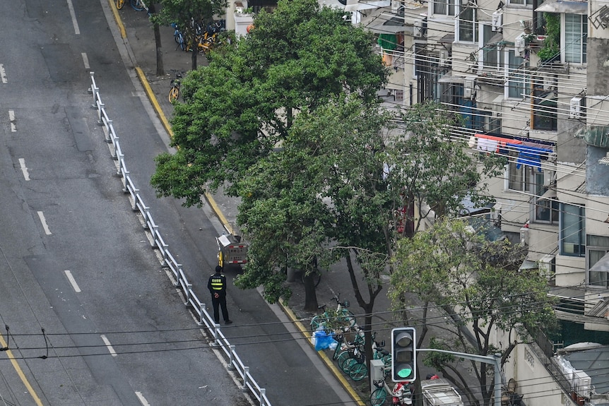 空中拍摄的上海一条空荡荡的街道，一名孤独的警察站在马路上。