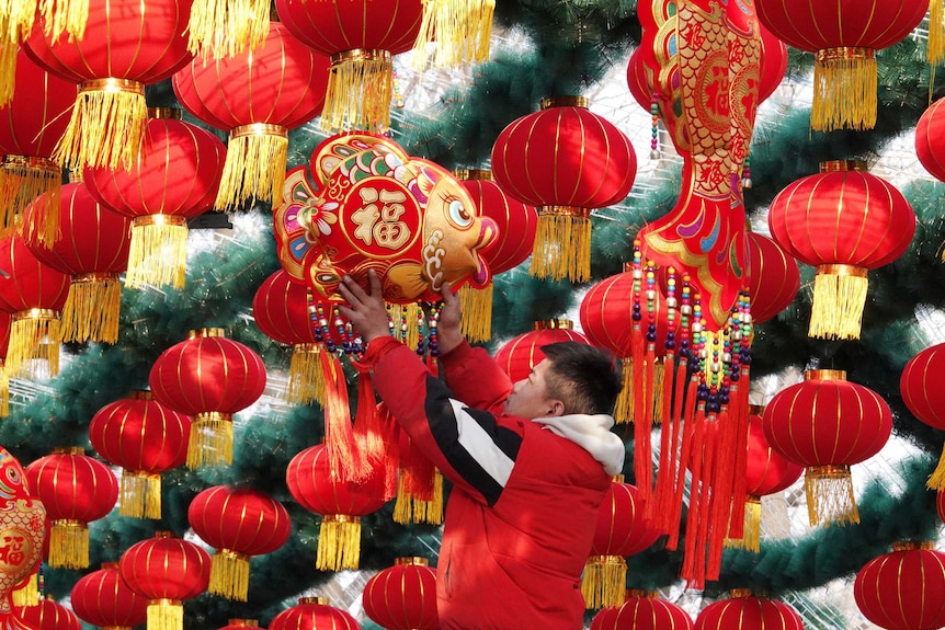 A staff member hangs decoration for a lantern arch at a park ahead of the Chinese Lunar New Year.