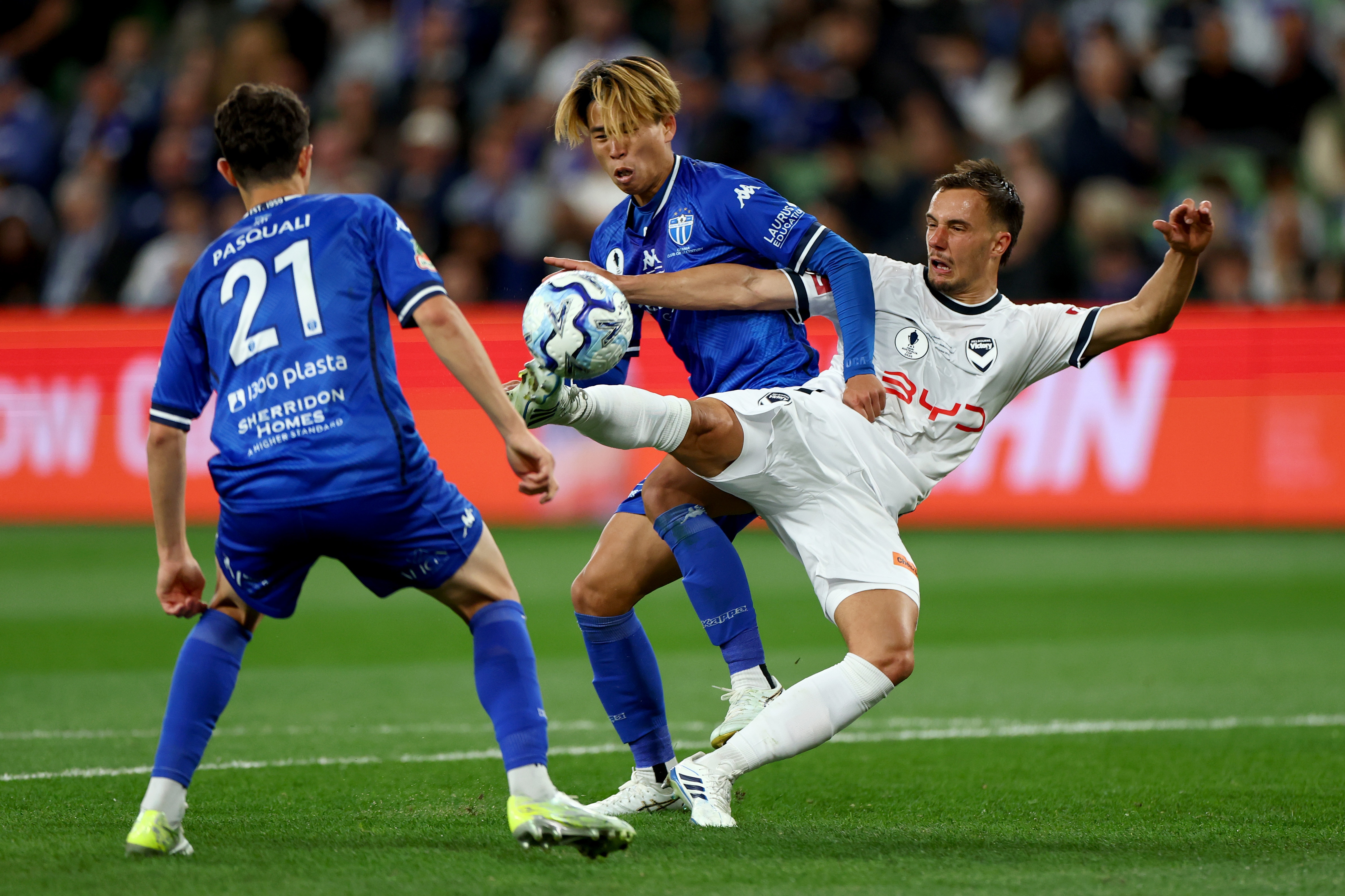 A Melbourne Victory soccer player volleys the ball towards goal while surrounded by South Melbourne defenders.