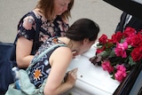 A woman kisses a coffin.