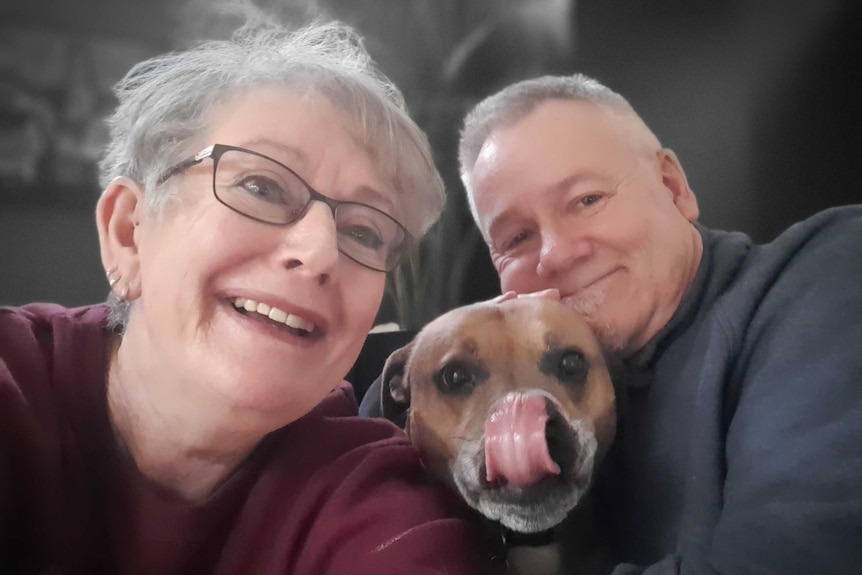 A smiling woman and man and their dog.
