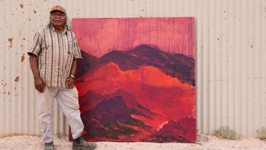An artist holding up his painting. 