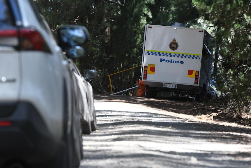 White forensics van parked on a road with forest in the background. 