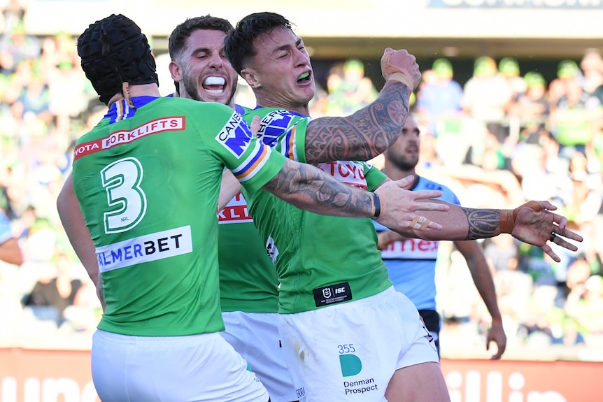 Three Canberra Raiders NRL players celebrate a try against Cronulla.