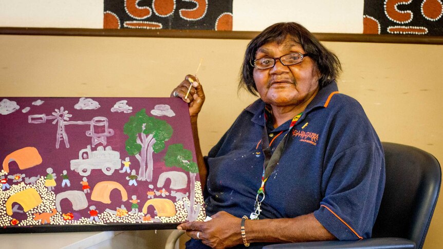 Artist Martha Ward with one of her pieces, created as part of an aged care painting project run by the Warakurna Art Centre.