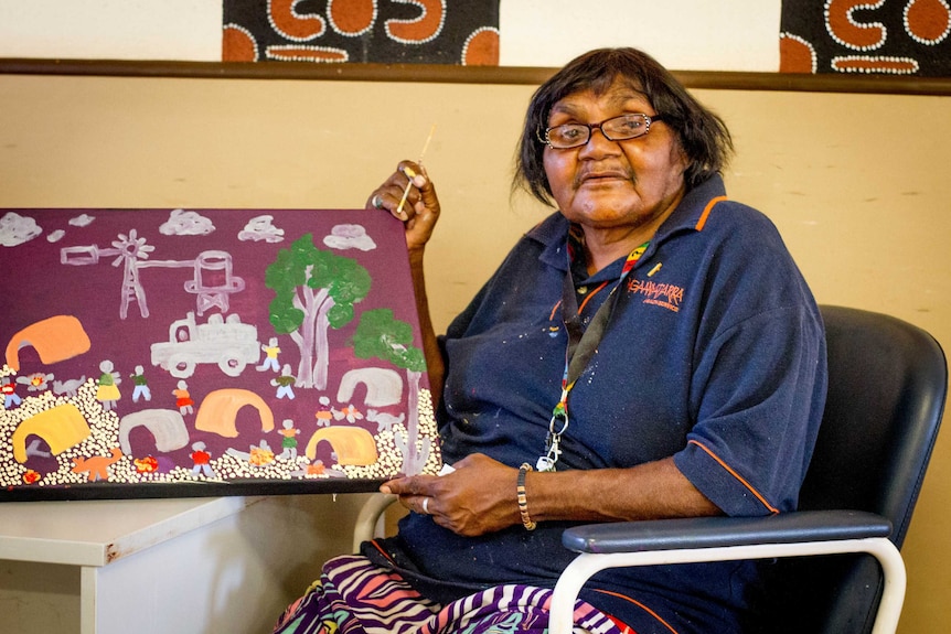 Artist Martha Ward with one of her pieces, created as part of an aged care painting project run by the Warakurna Art Centre.