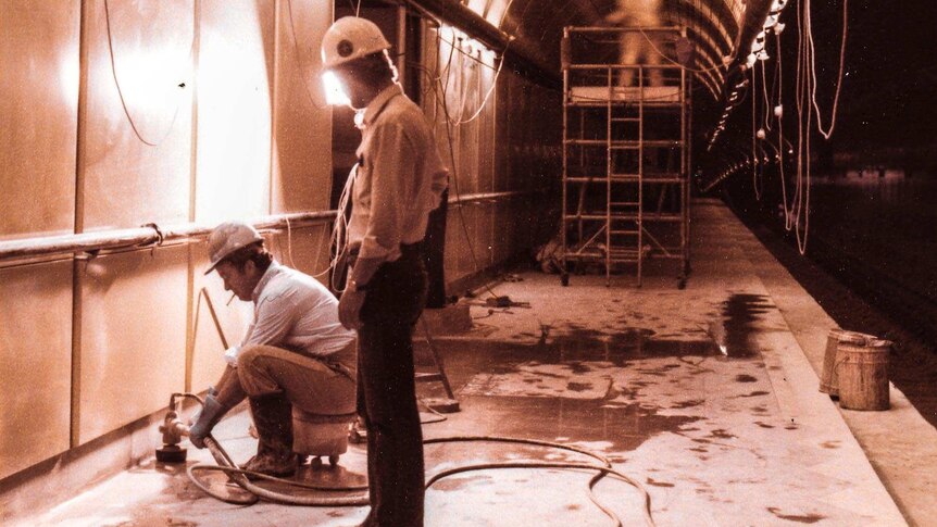 Workers prepare the floor and ceiling of an underground rail platform