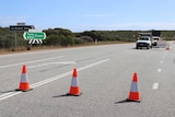 Emergency cones stretch across Indian Ocean Drive, with trucks in the background.