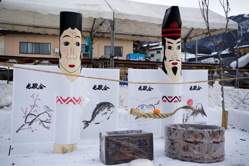 A group of wooden Dosojin statues in the snow at Nozawa Onsen.