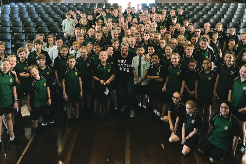 Woman standing in the middle of a couple of hundred school students.