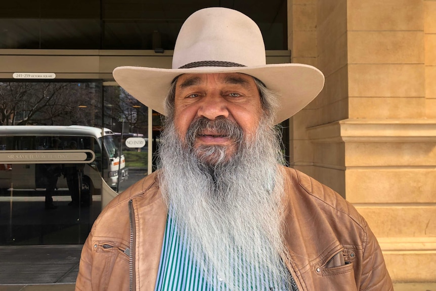 An older man with a long grey beard and moustache in front of a building in Adelaide.