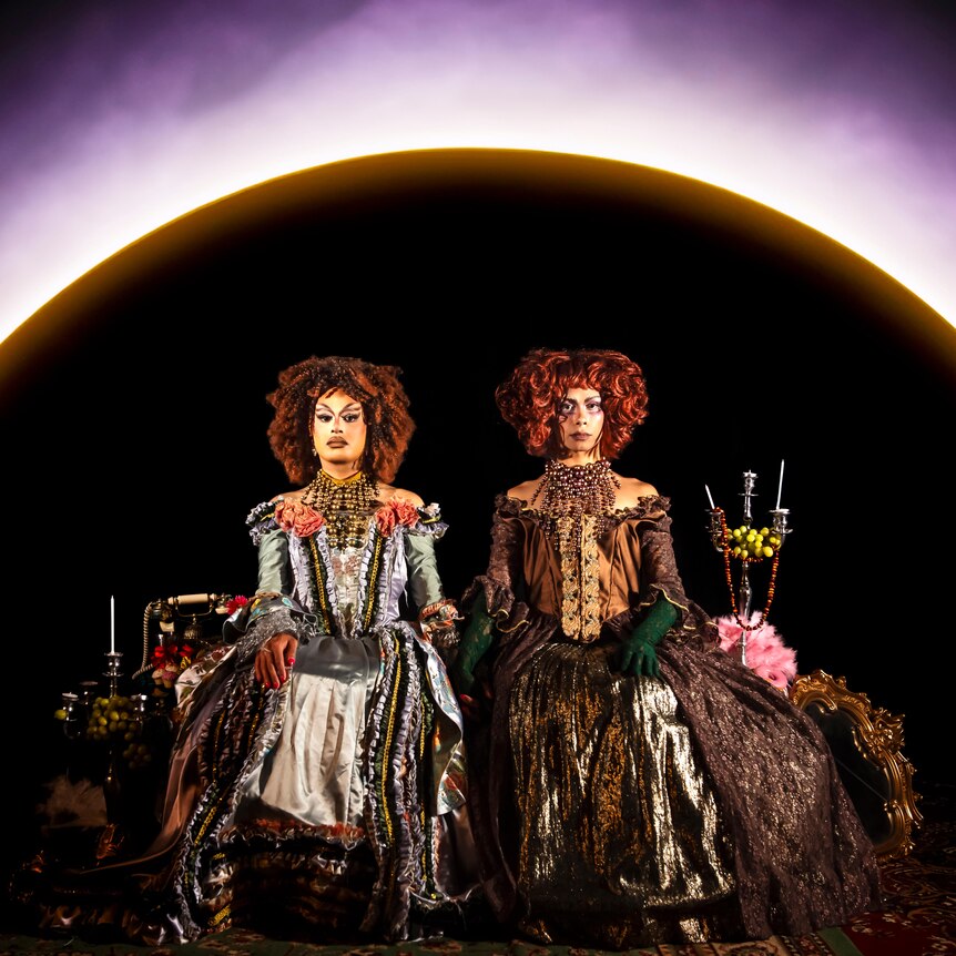 Cerulean and Stone Motherless Cold are sitting in front of an eclipse wearing period costumes.