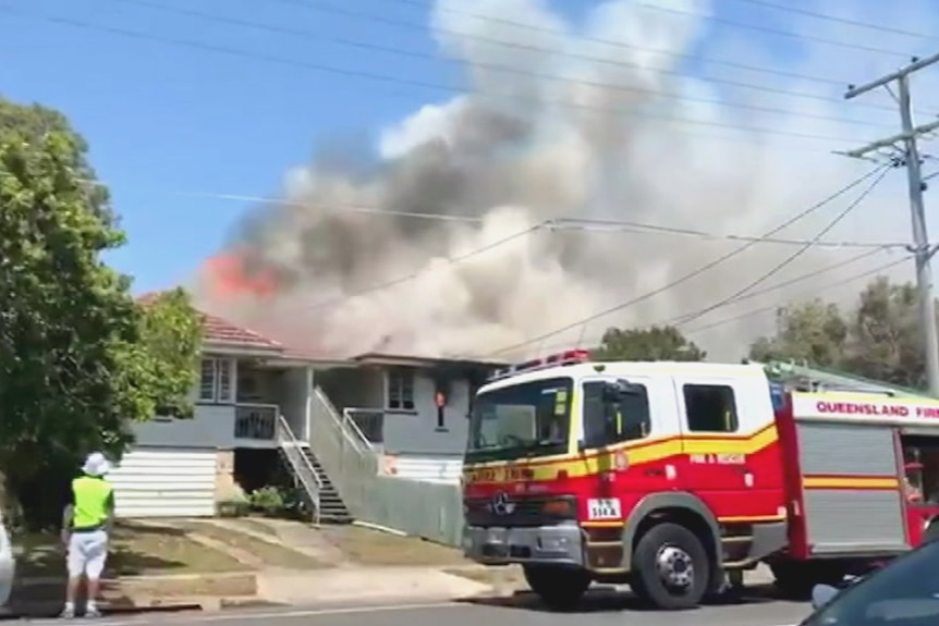 A fire engine outside a burning house