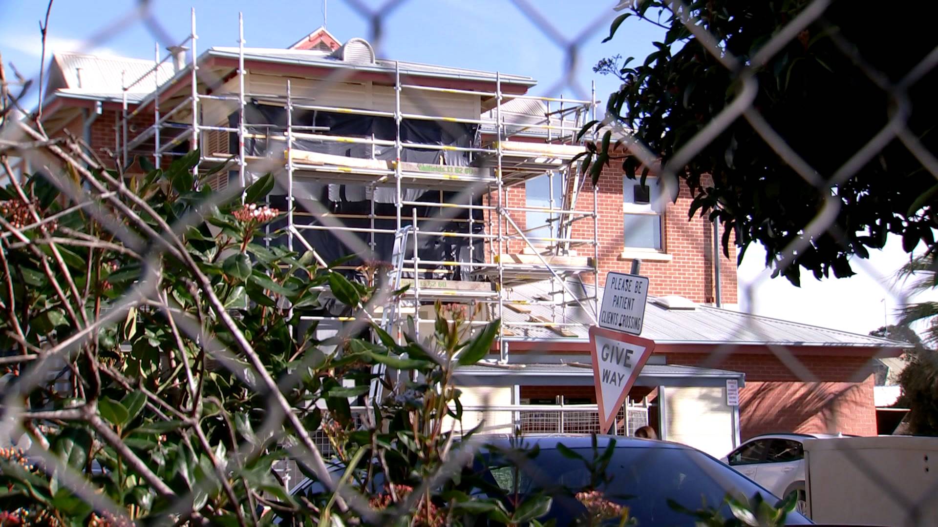 A two-storey building behind a mesh fence.