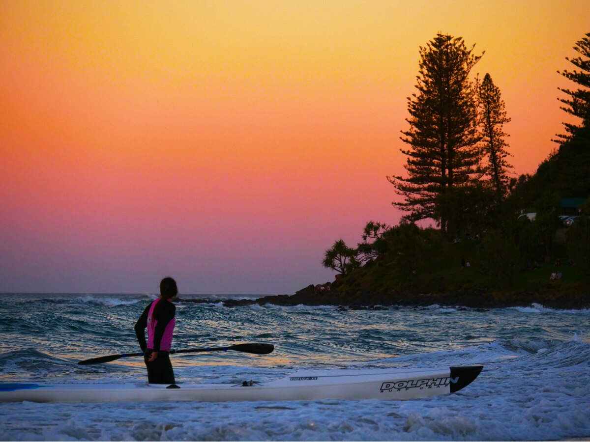 Sunrise over the ocean with paddle surfer in the foreground