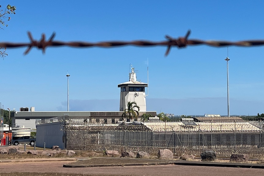 The exterior of the Don Dale Youth Detention Centre, with barbed wire in the foreground. 