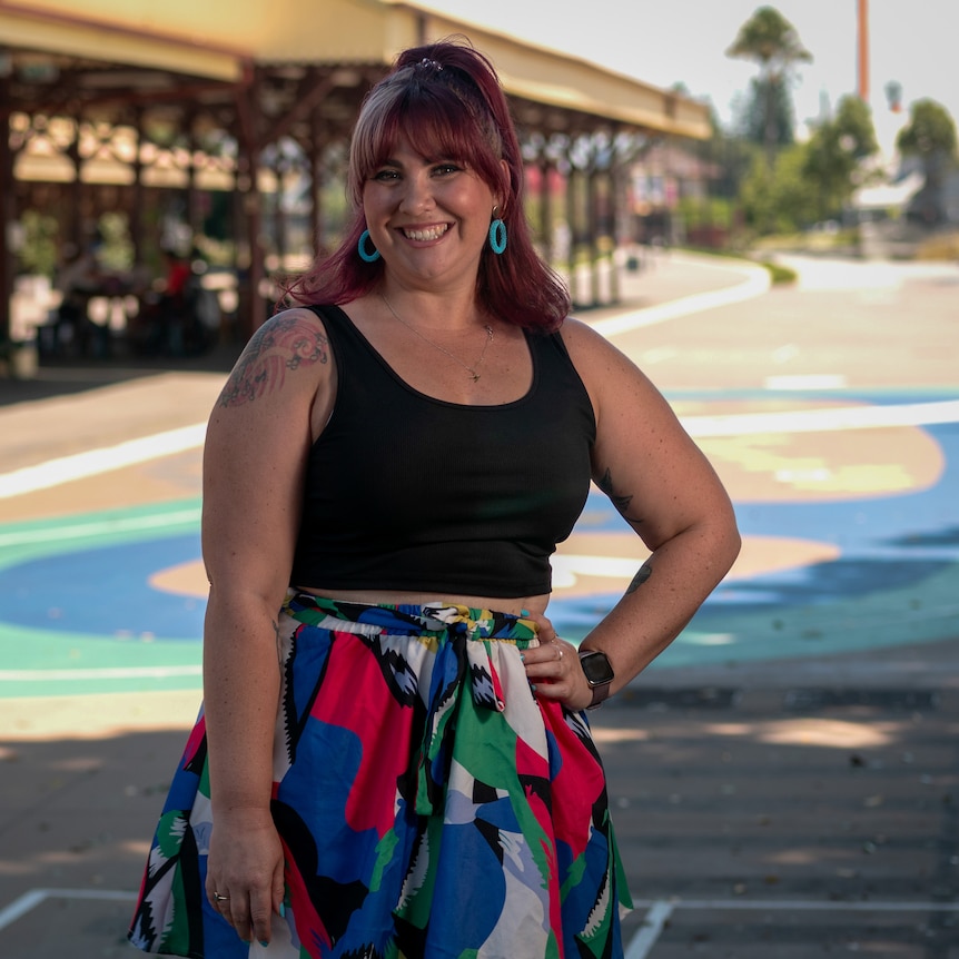 Kia Handley standing in front of a platform at the Newcastle train station, with art drawn on the walkway behind her.