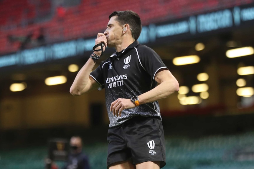 Pascal Gaüzère blows his whistle and holds his other arm down by his side in an empty stadium