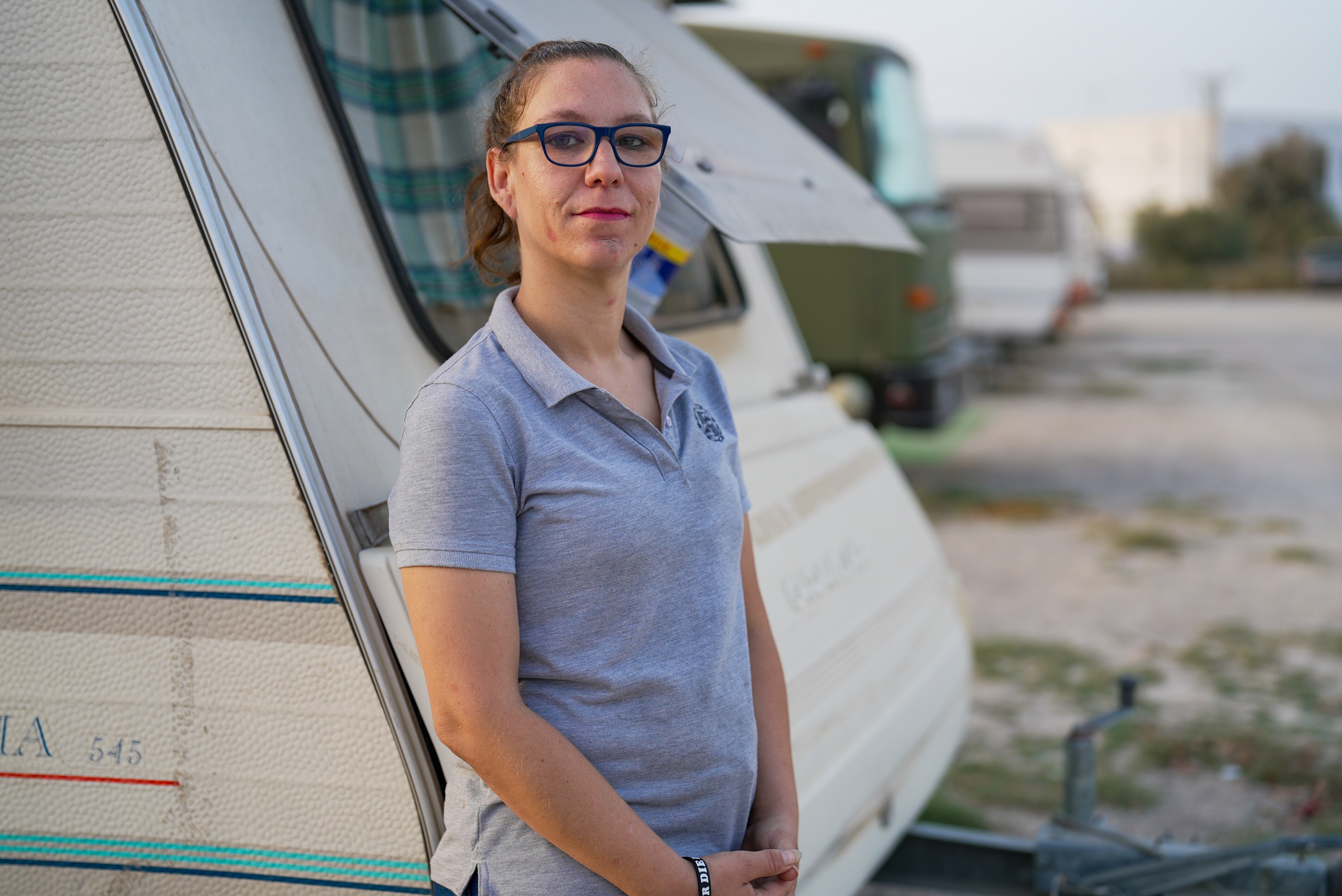 A woman stands in front of her caravan.