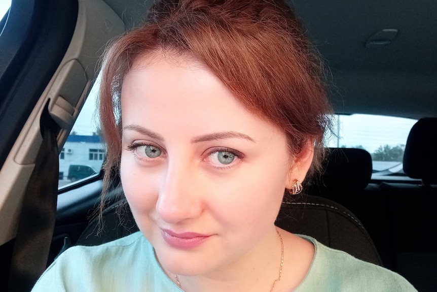 A woman with green eyes and red hair in a selfie. 
