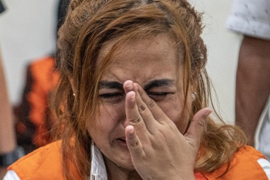 An Indonesian woman crying with her hand at her face.