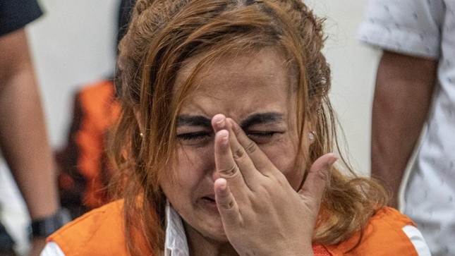 An Indonesian woman crying with her hand at her face.