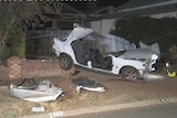 A car lies ripped apart after crashing in the front yard of a Northam property.
