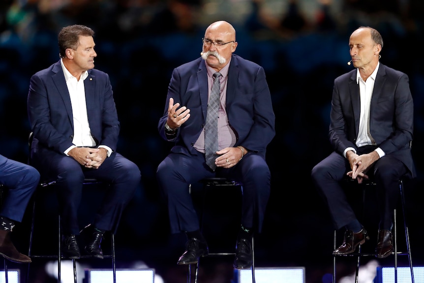 Cricketers Mark Taylor, Merv Hughes and Nasser Hussain sit on stools at Shane Warne's memorial.