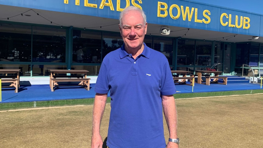 Burleigh Heads Bowls Club Chairman Paul Hynes standing on the green with clubhouse and sign behind him