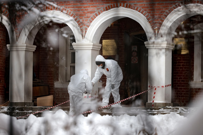 Forensic experts work at the entrance to the Orthodox school soon after the alleged bomber self-detonated, December 13, 2021.