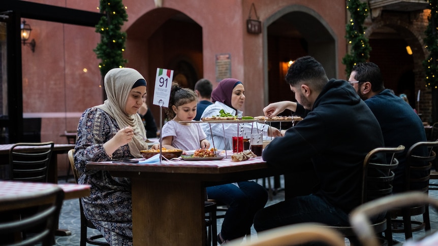 a family sitting at a table eating outdoors