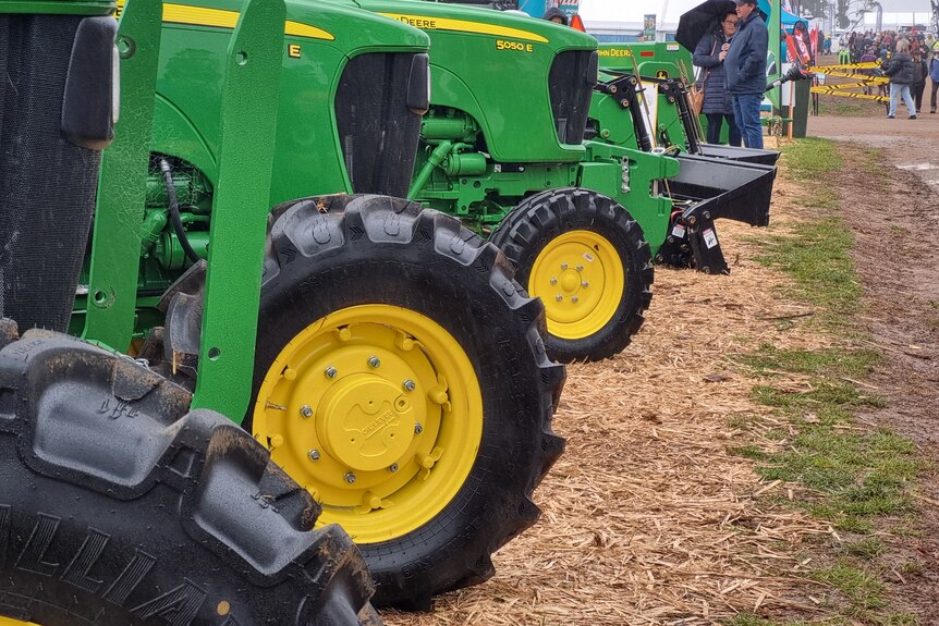 A row of green tractors next to each other at an agricultural field day