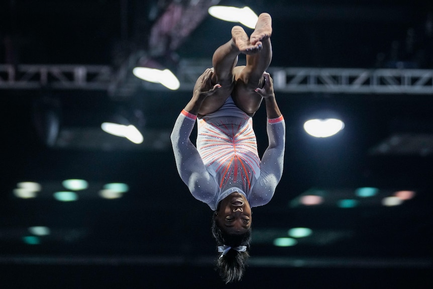 Simone Biles vaults with her legs straight